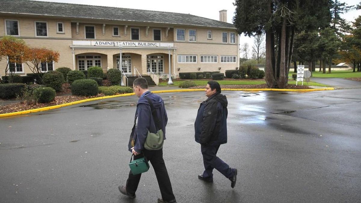 In a 2014 file photo, Pharmacy director William Hayes (left) and health services administrator Eric Hernandez walk across the empty Maple Lane School in Grand Mound on their way to the Department of Corrections new centralized pharmacy in the school's former woodshop building.