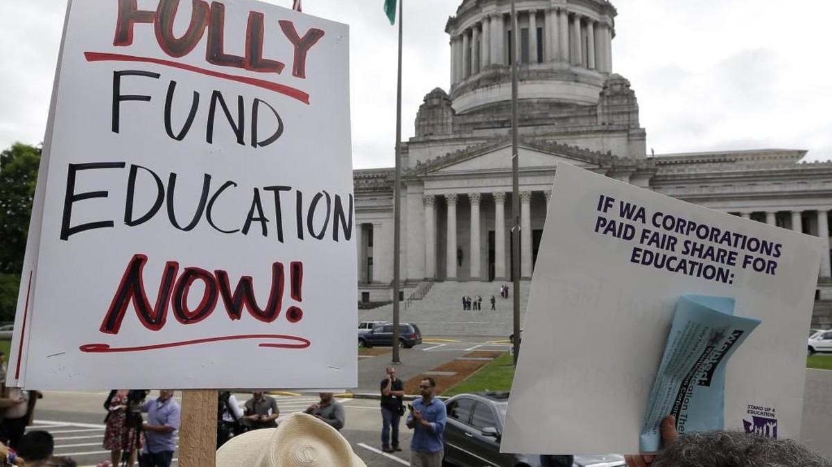 A small group of demonstrators stand on the steps of the Temple of Justice and in view of the Legislative Building as they advocate for more state spending on education prior to a hearing before the state Supreme Court Wednesday, Sept. 3, 2014, in Olympia, Wash.