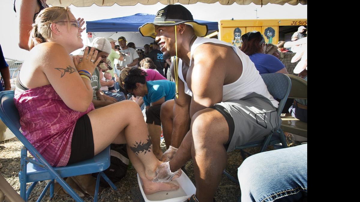 
Carolina Panthers running back Jonathan Stewart - a Timberline High graduate - chats with Robin Wills of Tumwater as he washes her feet during the weekly City Gates Ministries outreach in downtown Olympia on Wednesday, July 1, 2015. Stewart was joined by fellow NFL players and friends who also volunteered their help at the event, which gave away 500 pairs of new shoes on Thursday night.
