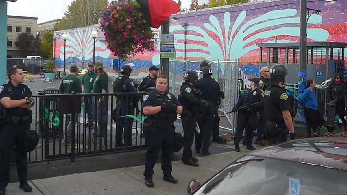 Olympia police and Thurston County Sheriff’s deputies guard the Artesian Commons Park as city parks staff put up the fence blocking the park.