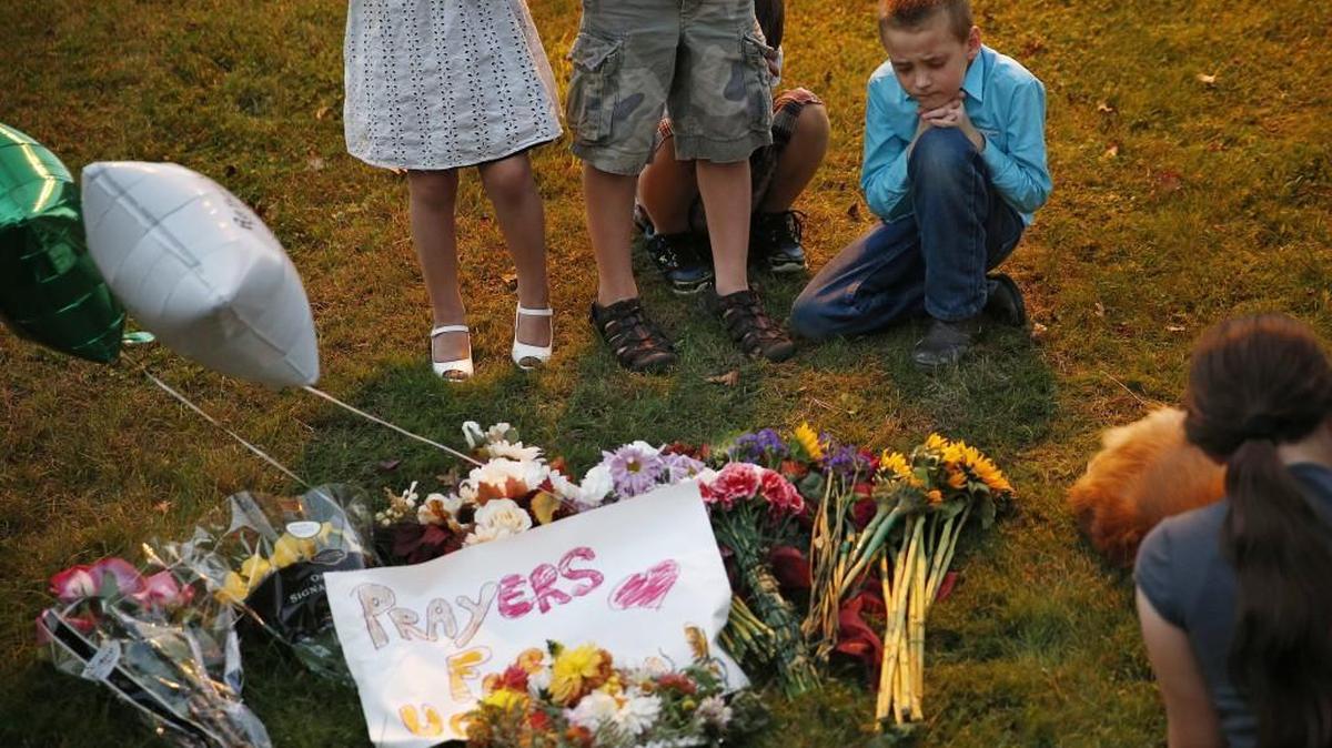 
Ethan Hurley, 7, top right, prays with a church group at a makeshift memorial near Snyder Hall at Umpqua Community College, Sunday, Oct. 4, 2015, in Roseburg, Ore. Armed suspect Chris Harper-Mercer on Thursday killed multiple people and wounded several others before taking his own life at Snyder Hall. 
