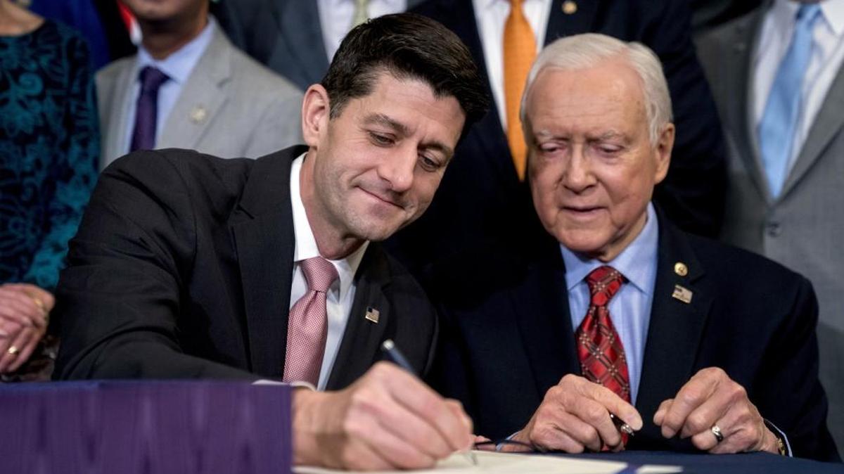 Speaker of the House Paul Ryan, R-Wis., center, accompanied by Senate Finance Committee Chairman Orrin Hatch, R-Utah, right, signs the final version of the GOP tax bill during an enrollment ceremony at the Capitol in Washington, Thursday, Dec. 21, 2017.