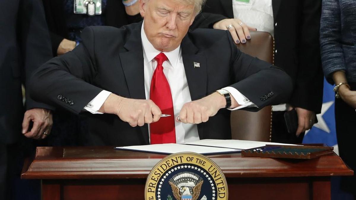 President Donald Trump takes the cap off a pen before signing executive order for immigration actions to build border wall during a visit to the Homeland Security Department in Washington