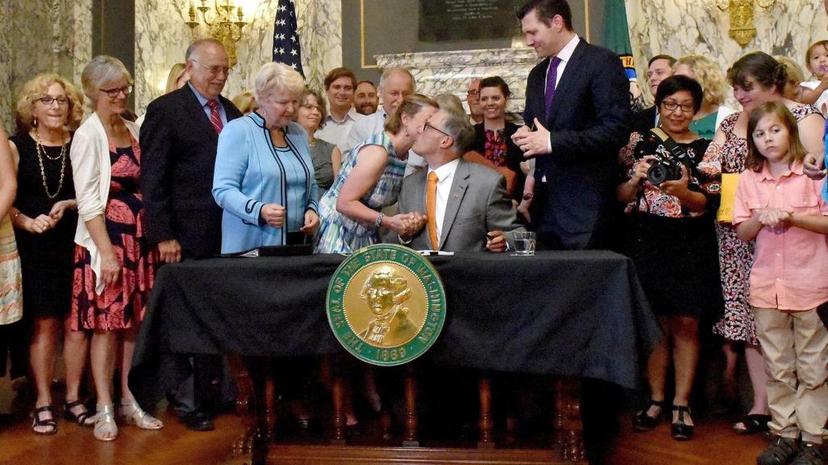State Rep. June Robinson, D-Everett, gives a kiss to Gov. Jay Inslee after he signed Senate Bill 5975 into law on July 5th which establishes paid medical and family leave in Washington state. Rep. Robinson was the prime sponsor of the bill in the House of Representatives.