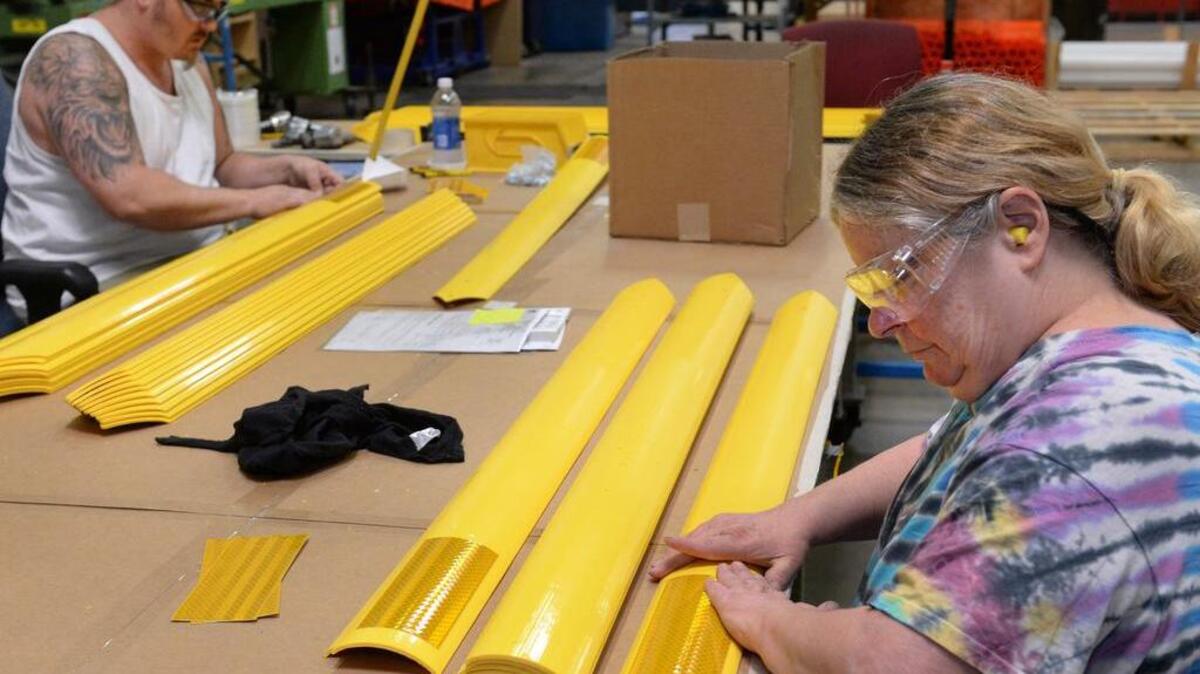 Fabricators Sarah Mosea, right, and Josiah Gibson apply reflective tape to traffic safety poles at Pexco's manufacturing center in Fife on Wednesday, June 11, 2014. The small company ships product in a variety of styles and colors all over the world. Federal insurance from the little known Export-Import Bank covers $2 million of Pexco's sales.