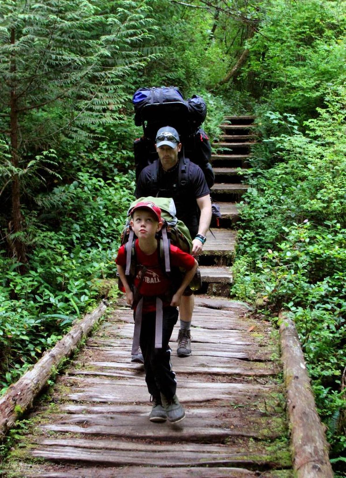 A father and son hike the boardwalk trail between Lake Ozette and Cape Alava in Olympic National Park.