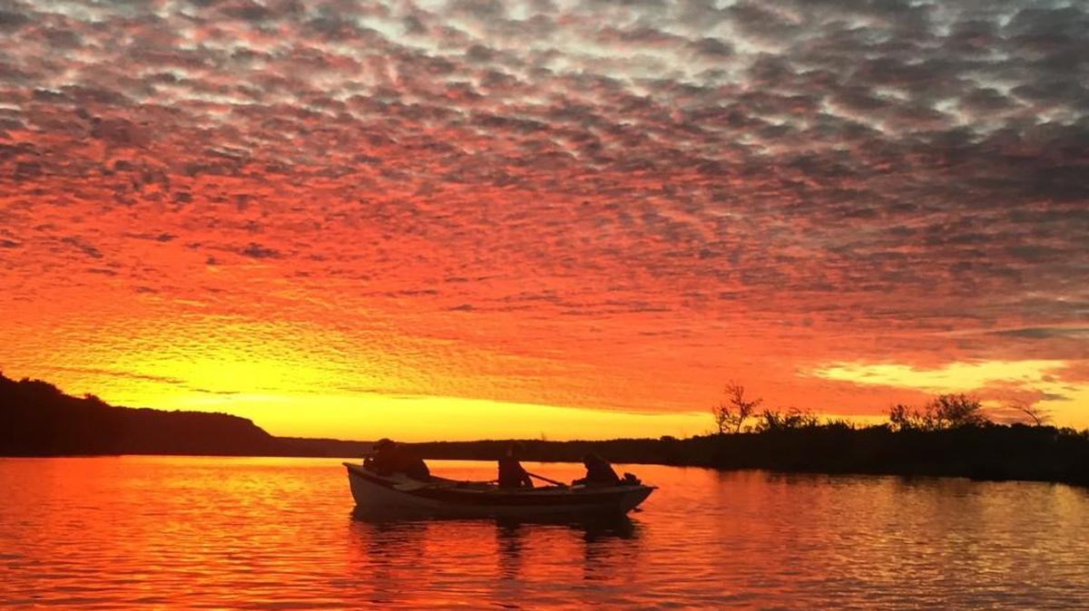 Sam Friedman, Audra Tromly and Eric Nathanson row at sunset in Minnesota. They are part of a University of Puget Sound group that is rowing the length of the Mississippi River.