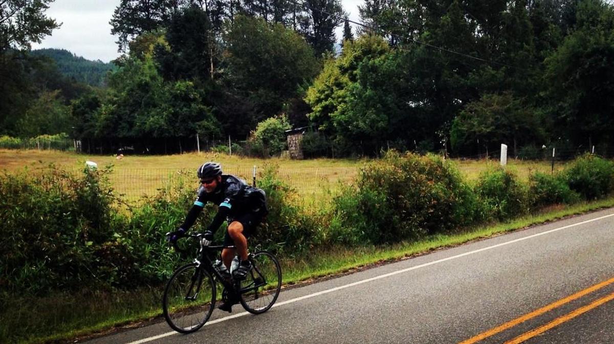 After spending a late-August morning riding to Windy Ridge in the rain and cold, Scott Wagar pedals back to Packwood with a garbage bag to protect him from the elements.