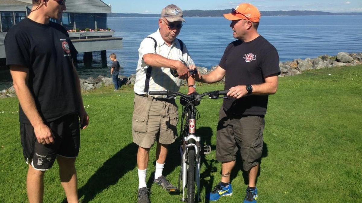 
Front from left, firefighter Evan Stanley watches as Jim Cook is presented a bike lock and refurbished bike from firefighter Dean McAuley. A fixture on the Tacoma waterfront, Cook had his bike stolen last summer. 
