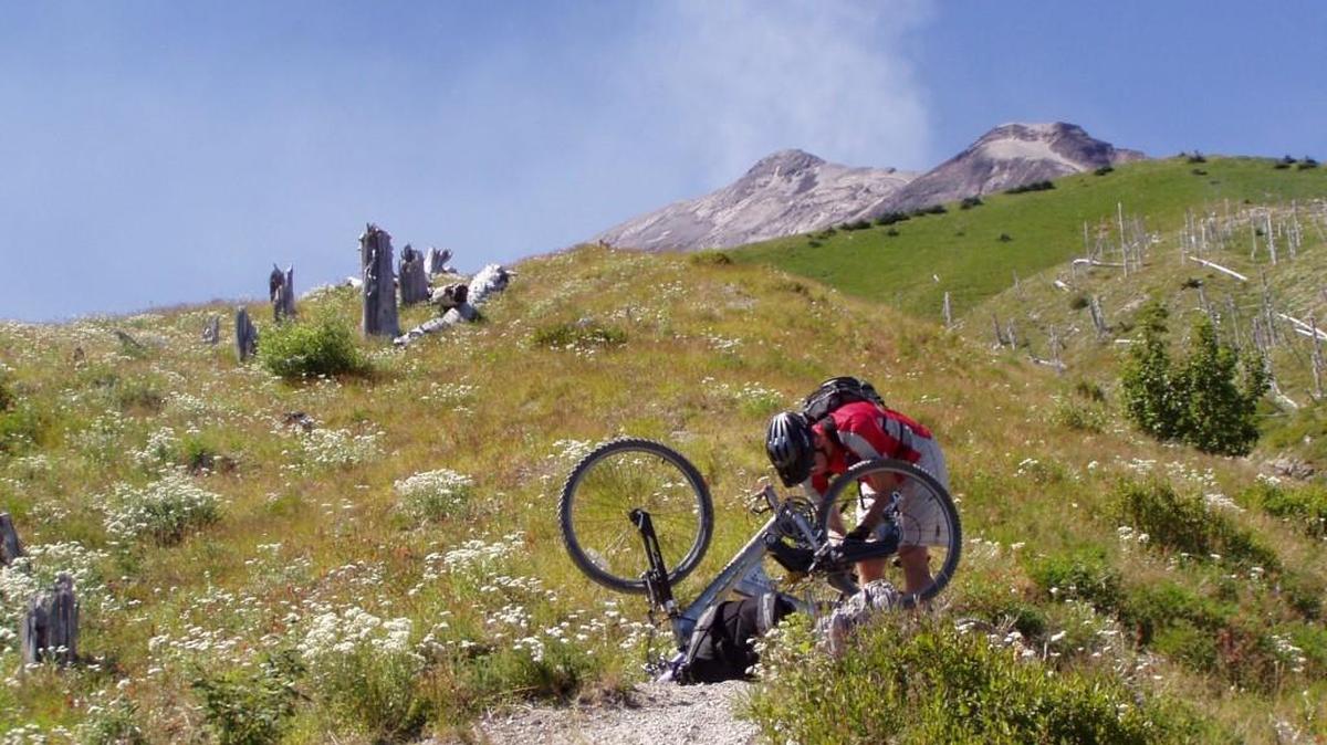 Kevin Sullivan of Puyallup attempts to make News Tribune writer Craig Hill’s bike rideable despite a bent back rim during a ride at Mount St. Helens. After being loved nearly to death, the bike found a new home courtesy of the Browns Point-based Bikes for Kids program.