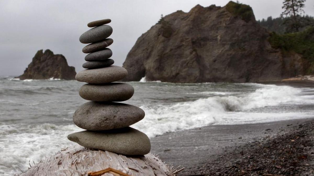 The keyhole of Hole-in-the-Wall can be spotted just to the right of this artful cairn on Rialto Beach in Olympic National Park.