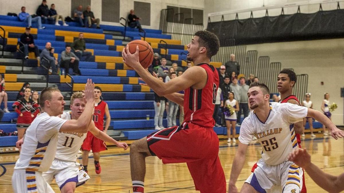 Yelm’s Christian Davis, center, scores two of his game-high 27 points Monday, splitting the defense of Jaden Vollmen, second from left, and Deven Neff.