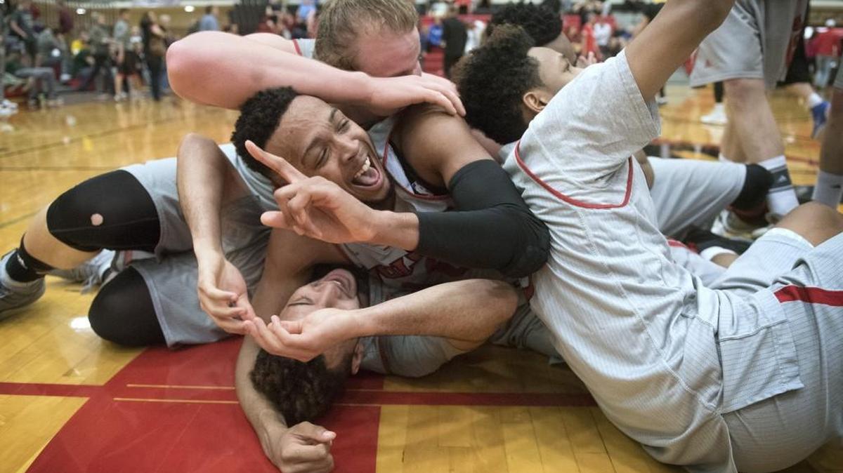 Western Oregon's Julian Nichol (top) and tournament MVP Devon Alexander are mobbed by teammates as time expires on the Wolves' 78-71 victory over Alaska in the GNAC Men's Basketball Championship game at Saint Martin's University in Lacey on Saturday, March 5, 2016.