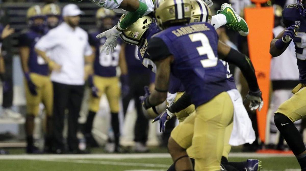 
Oregon wide receiver Darren Carrington eaps over Washington defensive back Budda Baker as Washington’s Darren Gardenhire (3) watches during the second half. 
