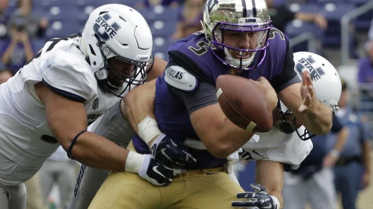 
Washington quarterback Jeff Lindquist fumbles as he is tackled by Utah State's Ricky Ali'ifua, left, and Kyler Fackrell, which led to a 97-yard touchdown return for the Aggies on Saturday at Husky Stadium.
