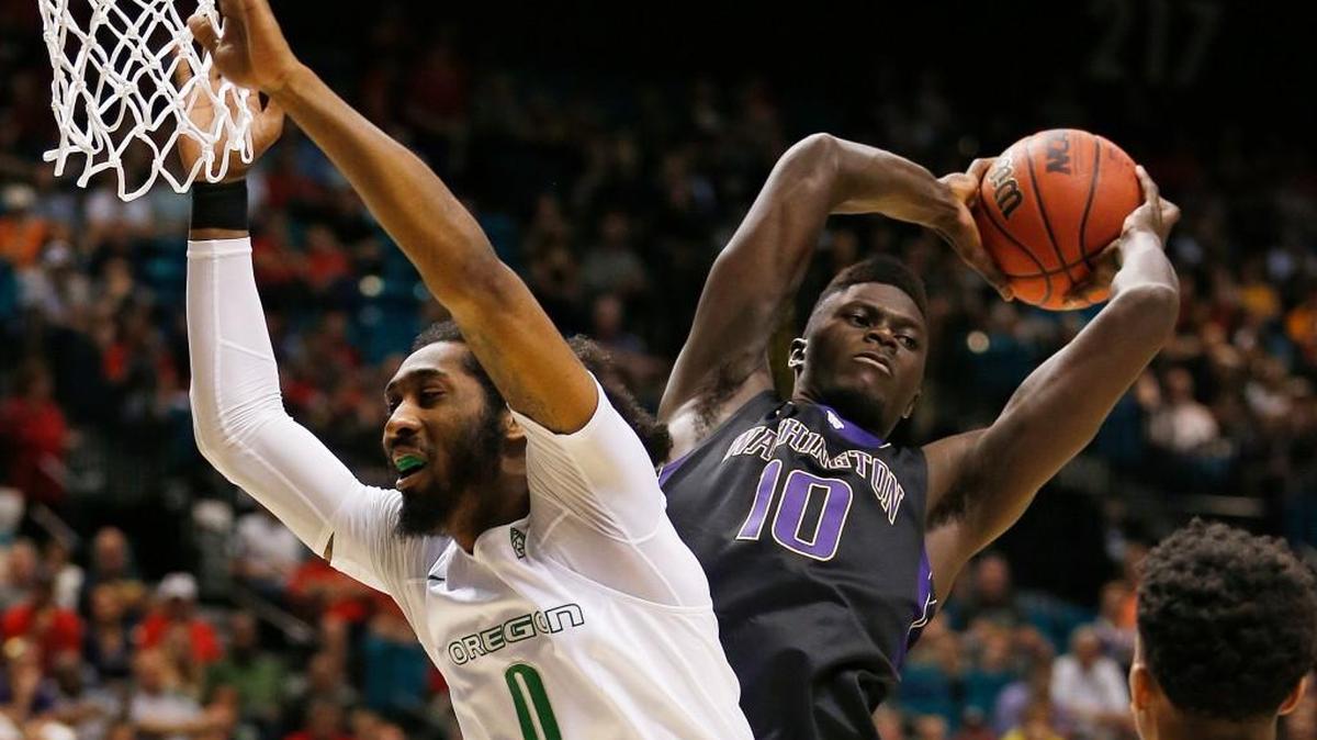 Washington forward Malik Dime (10) grabs a rebound over Oregon forward Dwayne Benjamin on Thursday during the Pac-12 tournament. The Huskies will find out their postseason future Sunday afternoon.