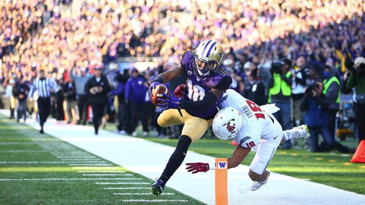 Washington’s Isaiah Renfro, left, makes a leap for the endzone against the defense of Washington State’s Shalom Luani during the first half of the Huskies’ 45-10 win in the 108th Apple Cup in November.