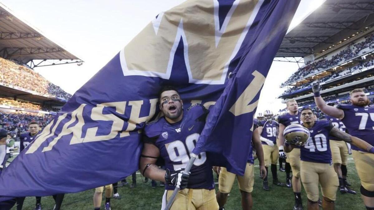 Taniela Tupou waves the University of Washington flag after the Huskies defeated Washington State in the Apple Cup on Nov. 27.