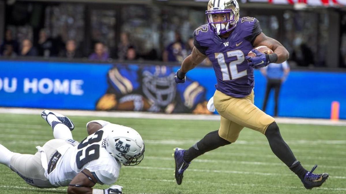 
UW tailback Dwayne Washington gains ground as Utah State linebacker Torrey Green falls in the first half. Photo taken at Husky Stadium in Seattle on Saturday, Sept. 19, 2015.
