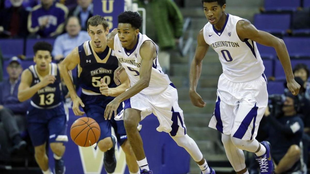 Washington guard Dejounte Murray, center, dribbles the ball past Mount St. Mary's center Taylor Danaher (50) as Washington forward Marquese Chriss, right, watches duirng the first half of an NCAA college basketball game, Thursday, Nov. 19, 2015, in Seattle.