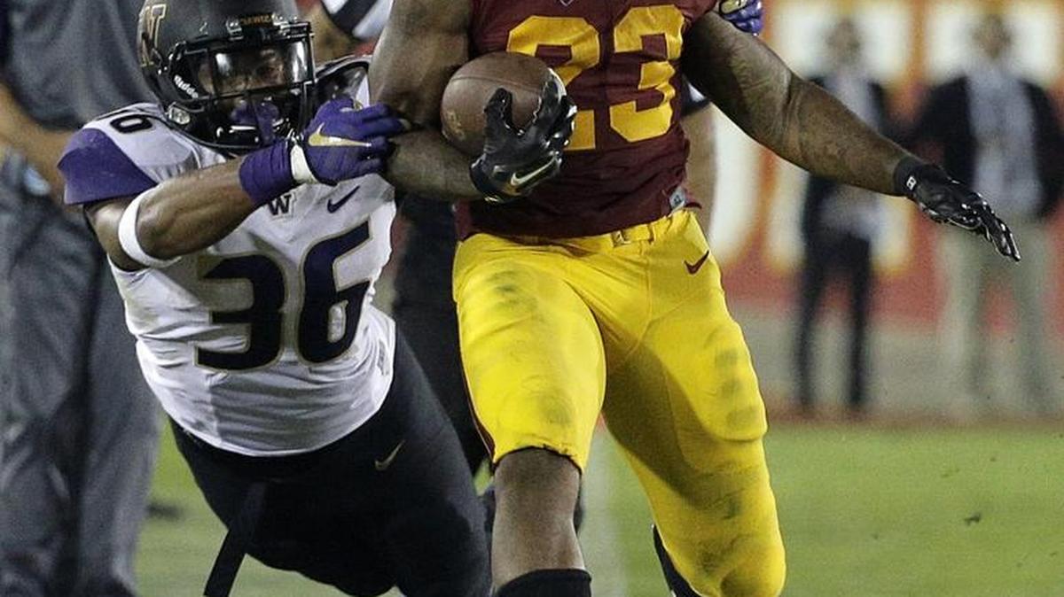 
Huskies linebacker Azeem Victor, left, grabs Trojans running back Tre Madden on Thursday. Victor was ejected later in the game for targeting USC quarterback Cody Kessler.
