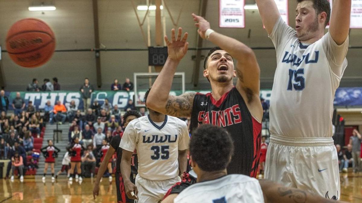 Saint Martin’s Cole Preston has the ball slapped away by Western Washington’s Taylor Stafford (1) Friday during a GNAC semifinal matchup between Saint Martin’s University and Western Washington men’s teams in Lacey.