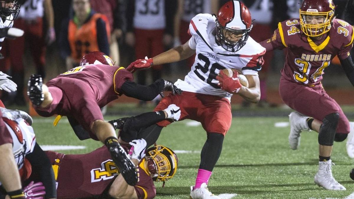 Capital defenders Jack Collard (4), Ryan Guscott (5) and Chad Garland (34) fight to bring down Yelm running back James Palmer (28) during Friday night’s game at Ingersoll Stadium in Olympia.