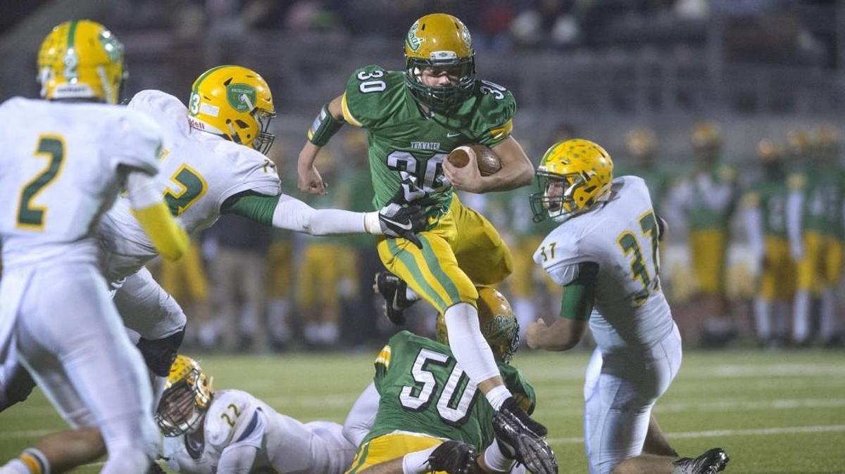 Tumwater running back Dylan Paine leaps teammate Cy Hicks (50) as he breaks past the Lynden defensive line during the opening round of the 2A state playoffs at Tumwater District Stadium on Nov. 9, 2017.