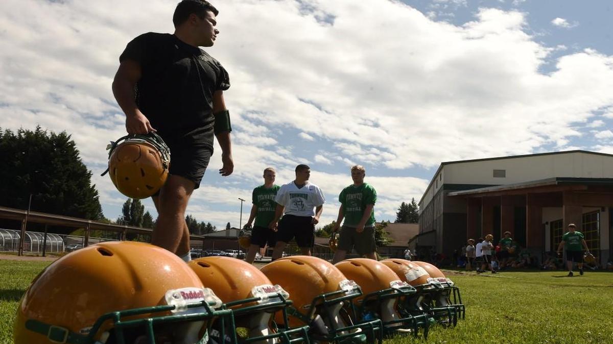 On the opening day of football practice last week at Tumwater High School, players pass by a row of Riddell SpeedFlex helmets that are designed to provide better protection. The Seattle Seahawks and United HealthCare presented the team with 25 of the concussion-tested helmets in May.