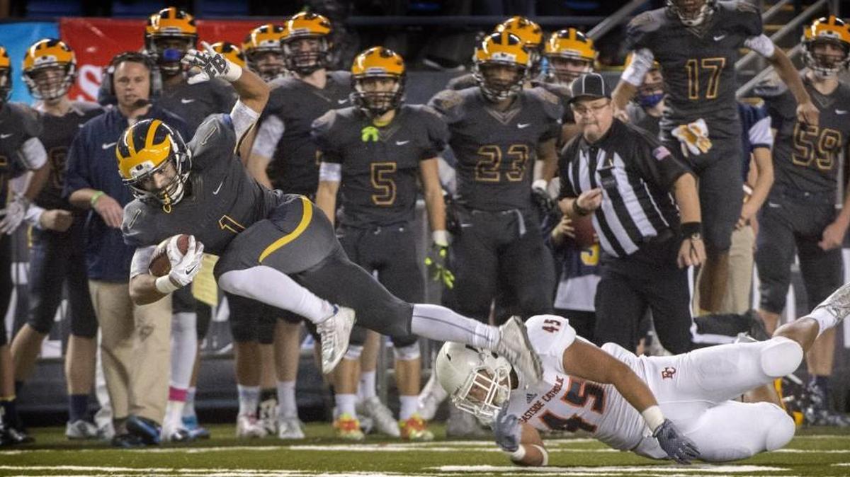 Bellevue's Isaiah Gilchrist flies to a first down while Eastside Catholic's Noah Failauga makes the tackle during 3A final game at the Tacoma Dome on Friday, Dec. 4, 2015.