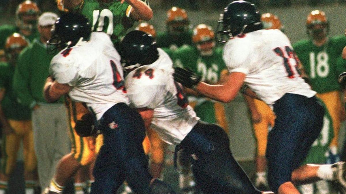 Tumwater quarterback Justin Gadomski loses the ball as he is hit by Black Hills defenders (from left) Chuck MacKenzie, Dante Cammarata and Spencer Gore on Oct. 23, 1999, during the first Pioneer Bowl game in Tumwater. Referees ruled that Gadomski’s arm was in motion and the play was ruled an incomplete pass. The T-Birds won, 31-28.