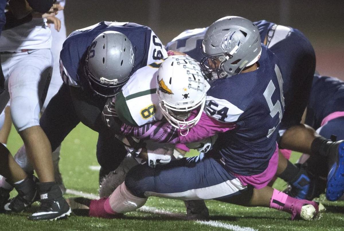 River Ridge defenders Griffin Adams (60) and Mika Faaitu (54) wrap up Clover Park running back Treyvon McDaniel for a loss during a football game at South Sound Stadium in Lacey on Oct. 12, 2017.