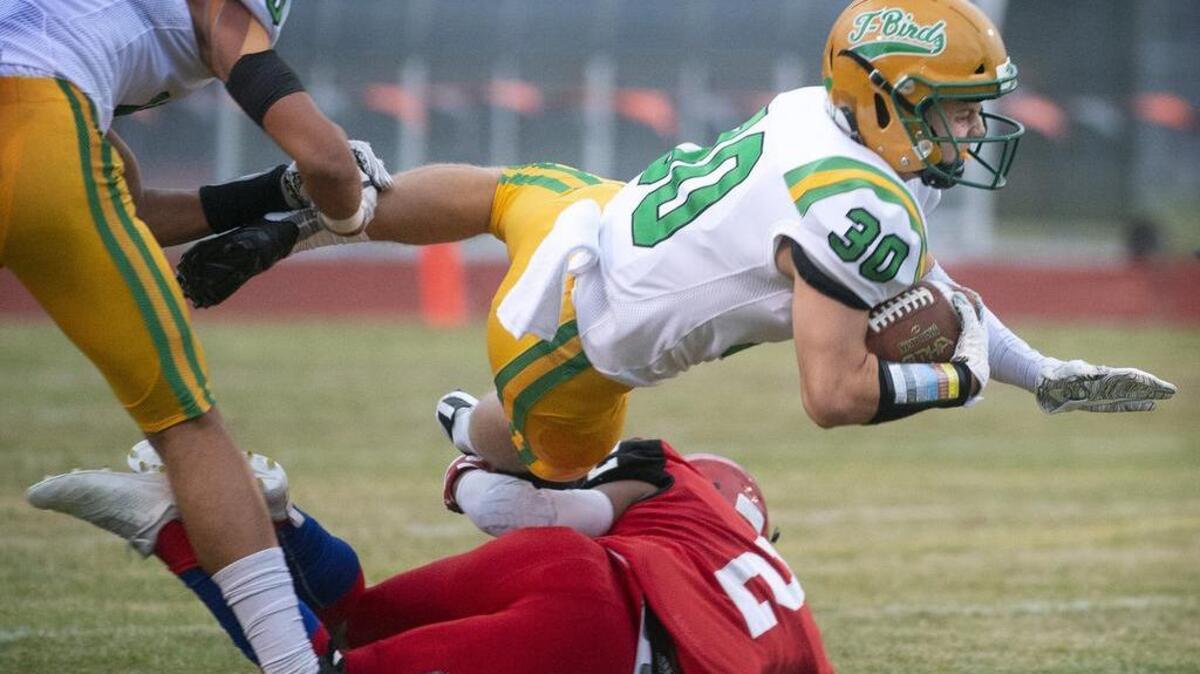 Tumwater running back Dylan Paine goes airborne in an attempt to elude Yelm defensive back Steven Reyes during Friday night’s football game at Yelm High School on Sept. 7, 2018.