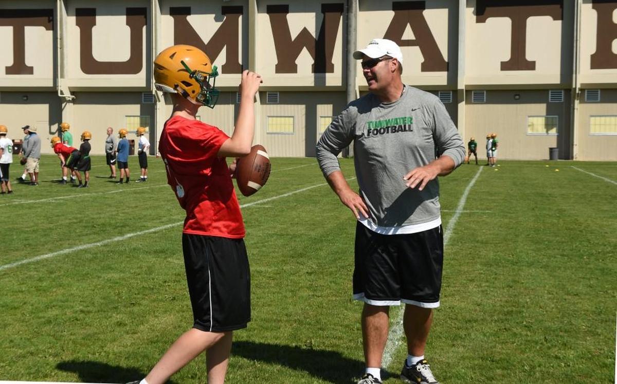 Tumwater coach Bill Beattie works with quarterback Elias Polito on his first day of practice in August. A former T-Birds player, Beattie took the reins from his mentor Sid Otton, who retired last season.
