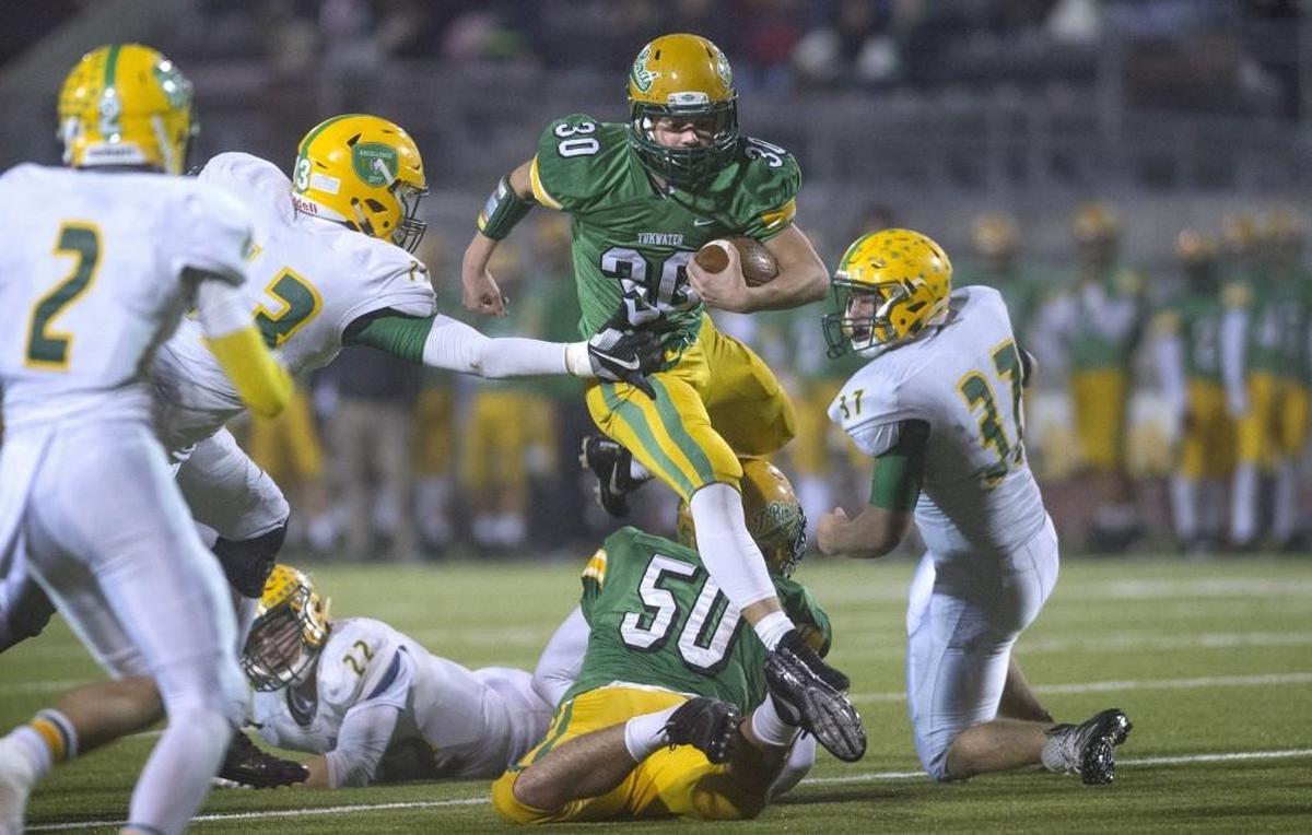 Tumwater running back Dylan Paine leaps teammate Cy Hicks (50) as he breaks past the Lynden defensive line during the opening round of the 2A state football playoffs at Tumwater District Stadium on Nov. 9, 2017.