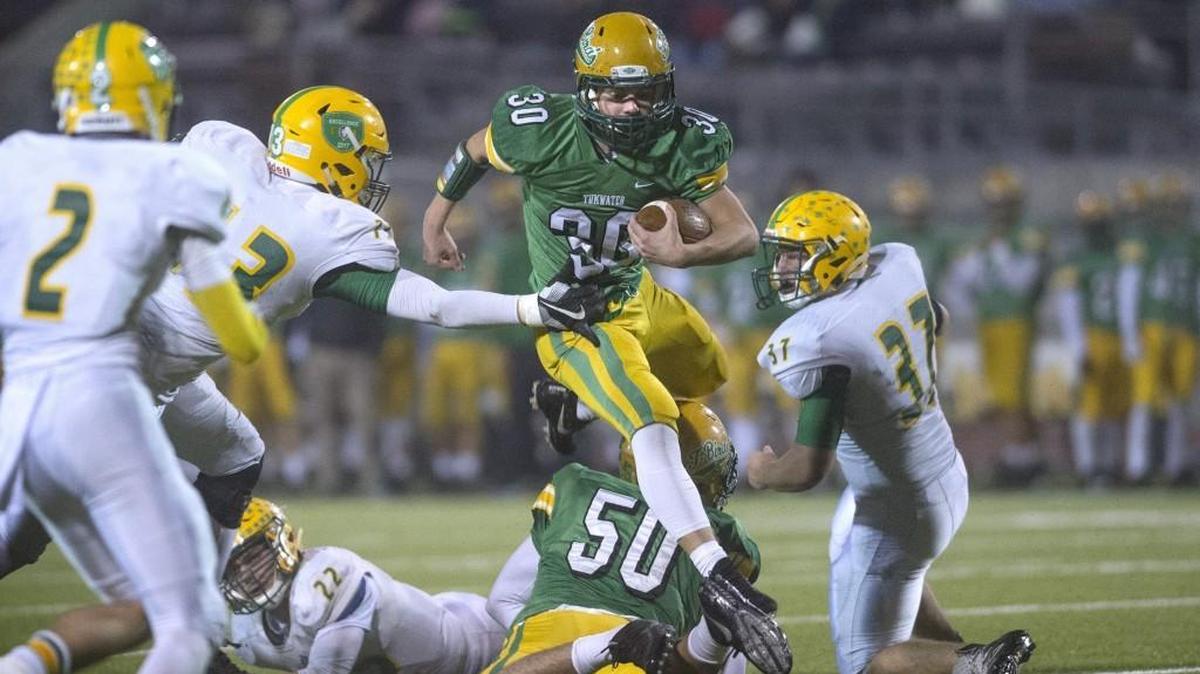 Tumwater running back Dylan Paine leaps teammate Cy Hicks (50) as he breaks past the Lynden defensive line during the opening round of the 2A state football playoffs at Tumwater District Stadium on Nov. 9, 2017.