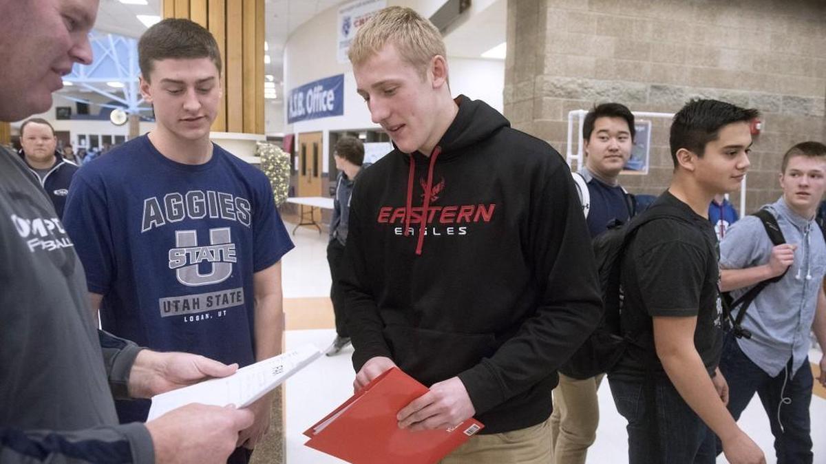 David Woodward, left, and Brett Thompson talk with football head coach Bill Beattie before a ceremony with classmates, coaches and staff at Olympia High School to celebrate their signing letters of intent to play football at Utah State and Eastern Washington respectively on Wednesday, Feb. 3, 2016.