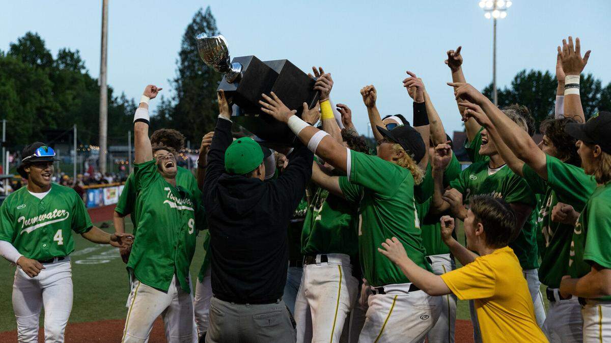 Tumwater athletic director Tim Graham hands the first-place trophy to the T-Bird baseball team after a 2-1 win in the 2A state title against Lynden at Joe Martin Stadium in Bellingham May 27.