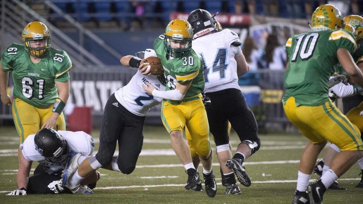 Tumwater running back Dylan Paine tries to break free from Hockinson linebacker Jake Beslanowitch (2) during Saturday's 2A state football championship game in the Tacoma Dome on Dec. 2, 2017.