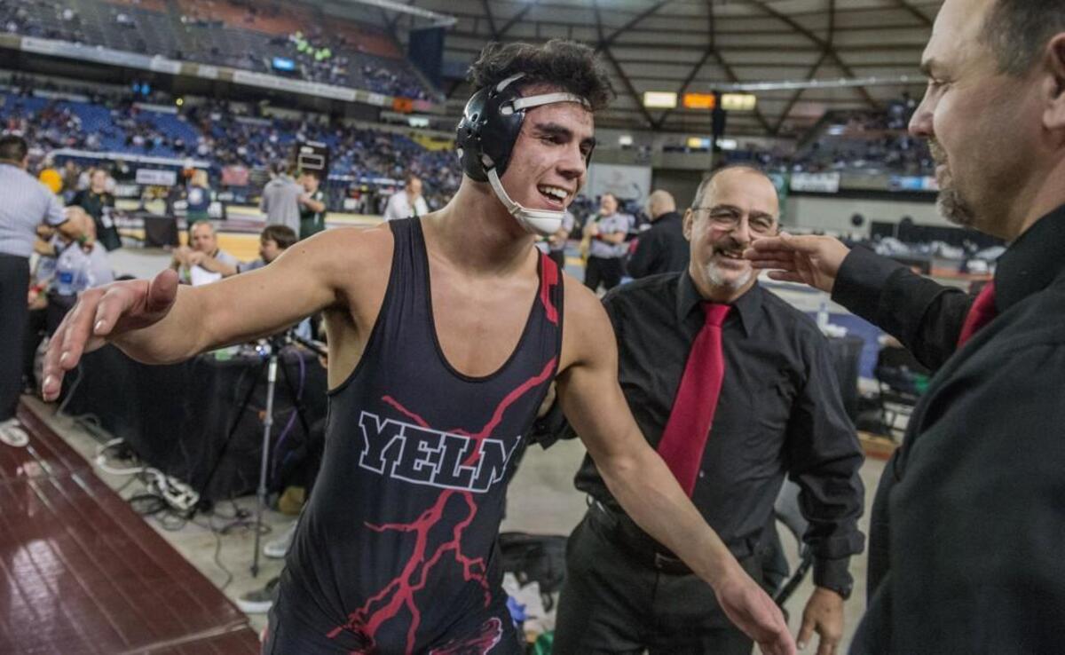 Derrick Platt of Yelm goes for a hug with his coaches after winning the boys 3A 182-pound weight class championship round of Mat Classic XXX, held in the Tacoma Dome, Feb. 17, 2018.