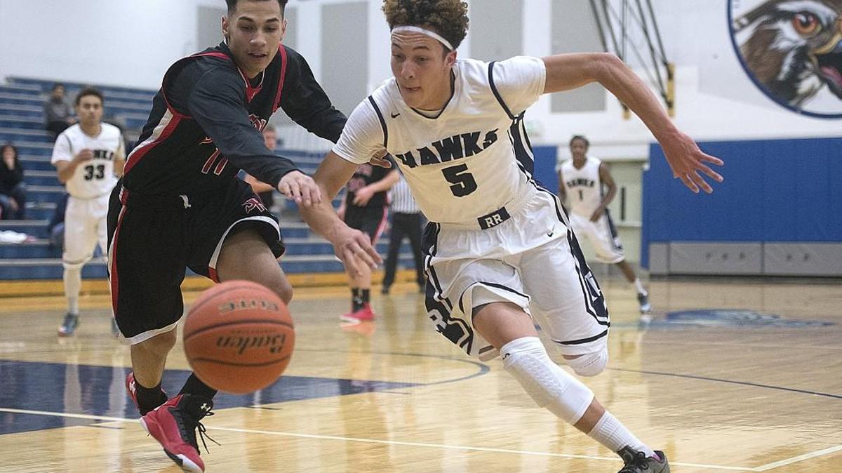 Shelton's Ty Fisher (left) and River Ridge's Tre Dorfner race to a loose ball during the two teams’ season opener at River Ridge High School on Tuesday. The Hawks played like a taeam in midseason form, winning 78-28.,