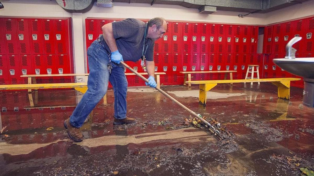 
Stadium High custodian Sem Kosanovskiy pushes a mess of mud and water left by flooding from Saturday's deluge out of the girls lockerroom on Monday.
