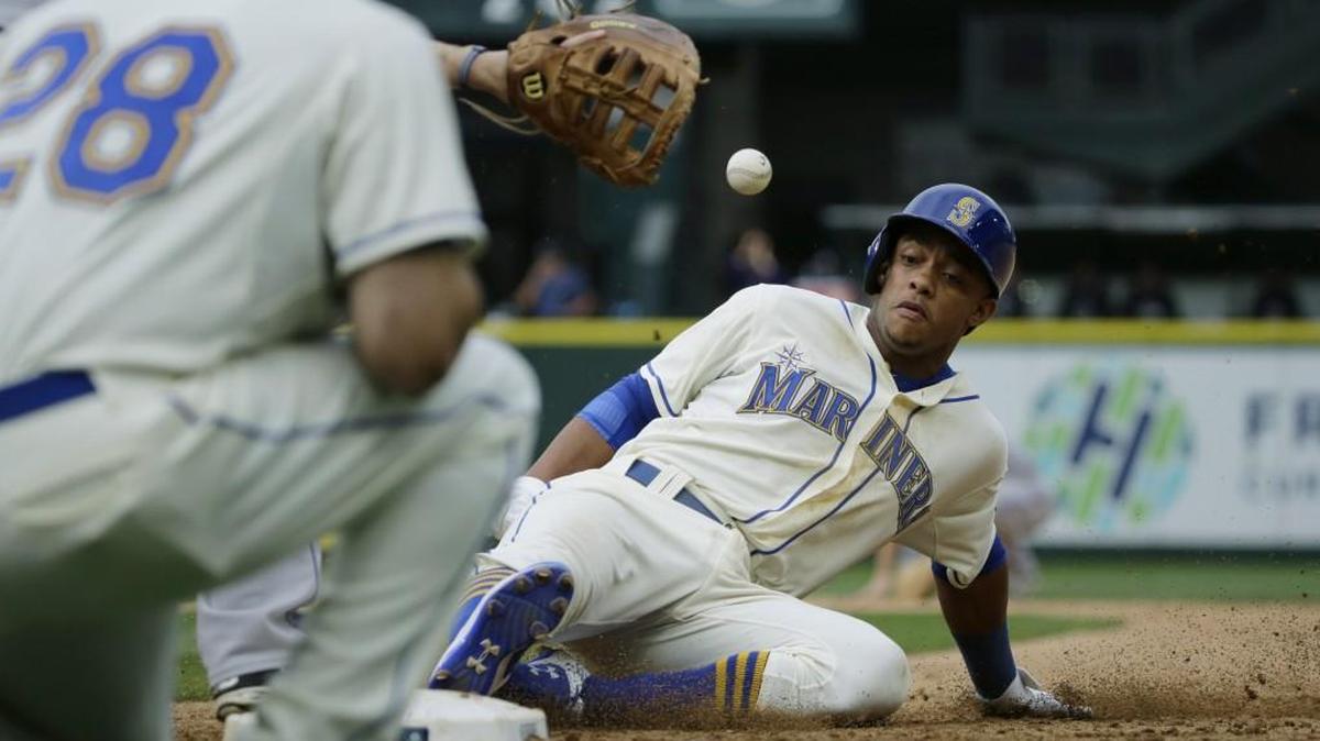 
The Mariners’ Ketel Marte slides back into first base as Colorado Rockies first baseman Justin Morneau catches the relay throw from shortstop Cristhian Adames on Sunday. Marte was out on double play, ending the eighth inning.
