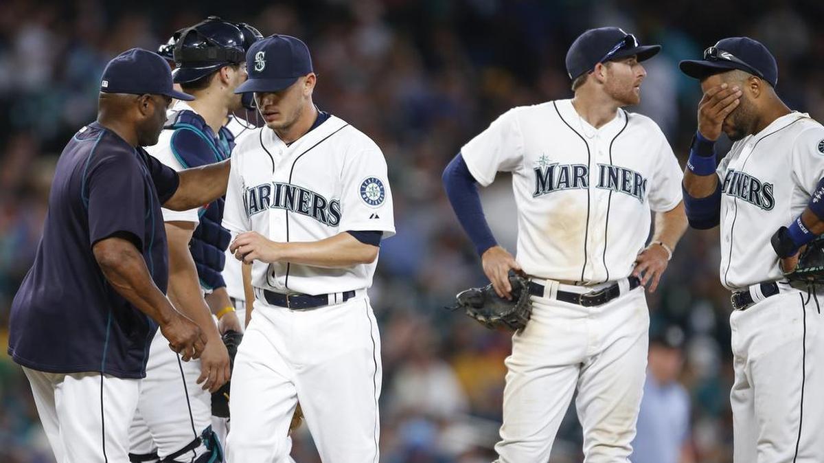 
Seattle Mariners pitcher Rob Rasmussen, third from right, walks to the dugout after being relieved by manager Lloyd McClendon, left, during the 11th inning. Mariners shortstop Brad Miller, second from right, and second baseman Robinson Cano, right, stand on the mound. 
