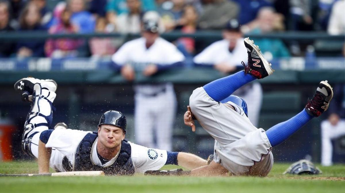 
Texas’ Rougned Odor, right, beats a tag by Mariners catcher John Hicksto score a run on a wild pitch during the seventh inning Monday at Safeco Field.
