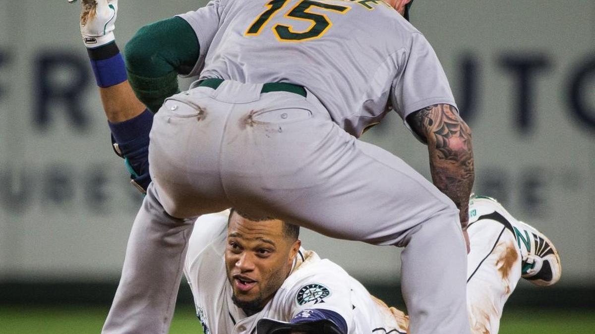 
The Mariners' Robinson Cano slides safely under the tag of Oakland shortstop Brett Lawrie (15) for a double in the seventh inning that made Cano the first player in MLB history to record 11 consecutive 30-double seasons to open a career.

