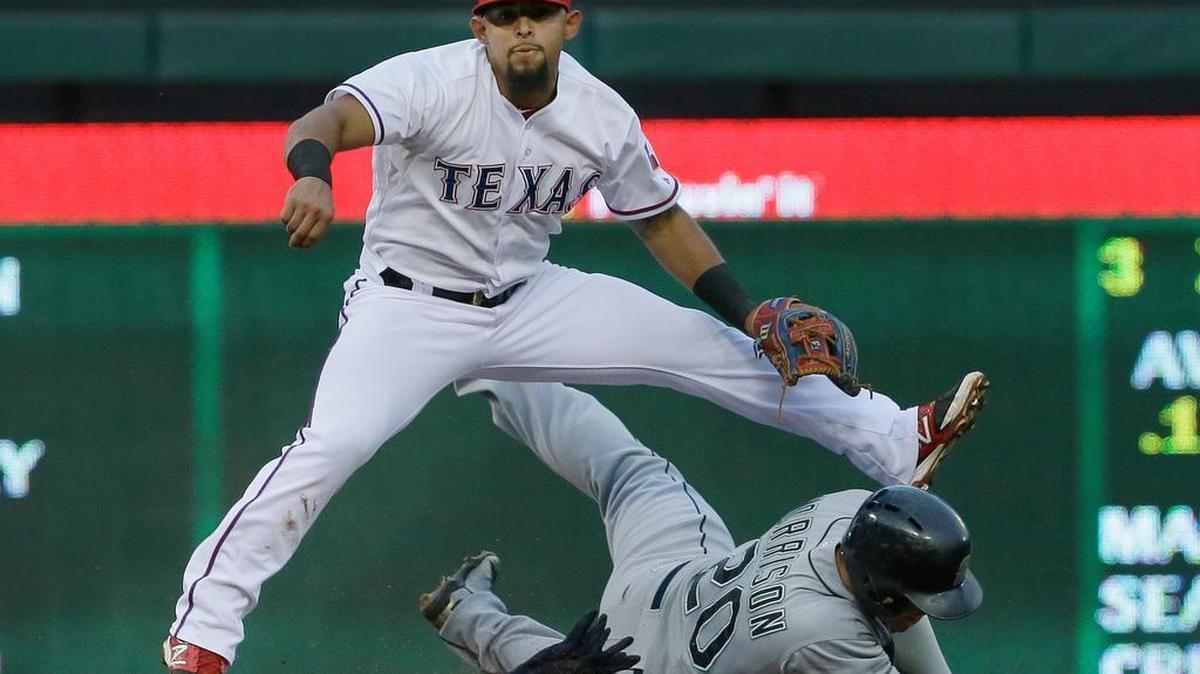 
Texas second baseman Rougned Odor, top, throws to first base to complete the double play over a sliding Logan Morrison of the Mariners in the third inning Monday in Arlington, Texas.
