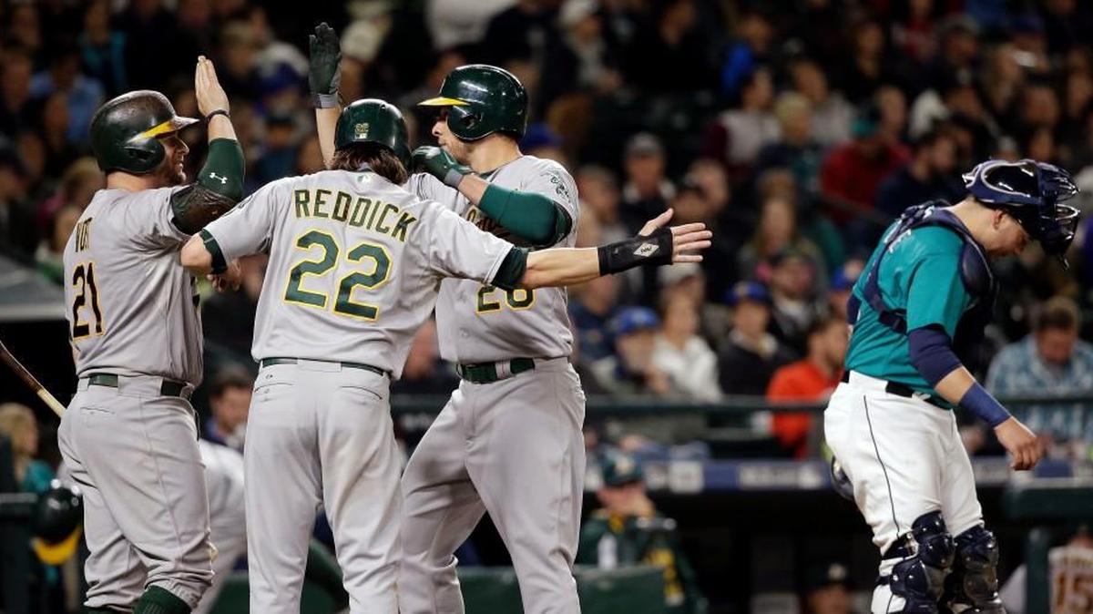 
The Oakland Athletics’ Stephen Vogt (21) and Josh Reddick (22) greet Danny Valencia after his two-run home run as Seattle Mariners catcher Jesus Sucre waits for the next batter in the eighth inning Friday.
