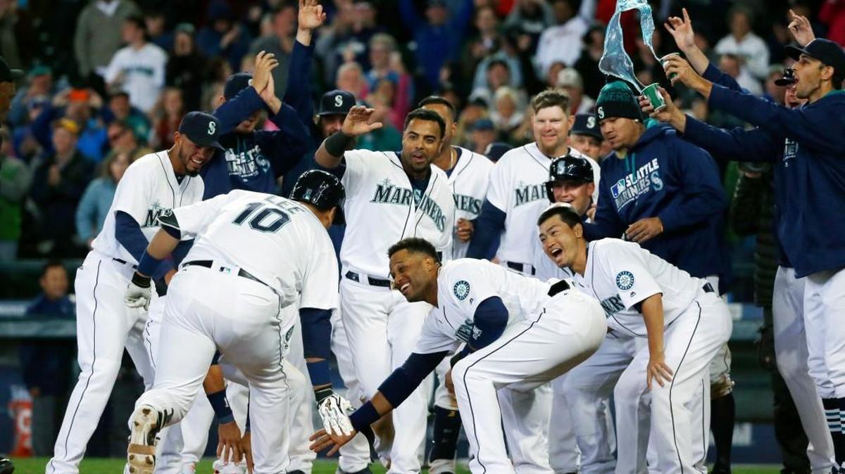 Seattle Mariners' Dae-Ho Lee (10) is greeted at the plate by teammates after he hit a walk-off two-run home run in the tenth inning of a baseball game against the Texas Rangers, Wednesday, April 13, 2016, in Seattle. The Mariners beat the Rangers 4-2 in ten innings.