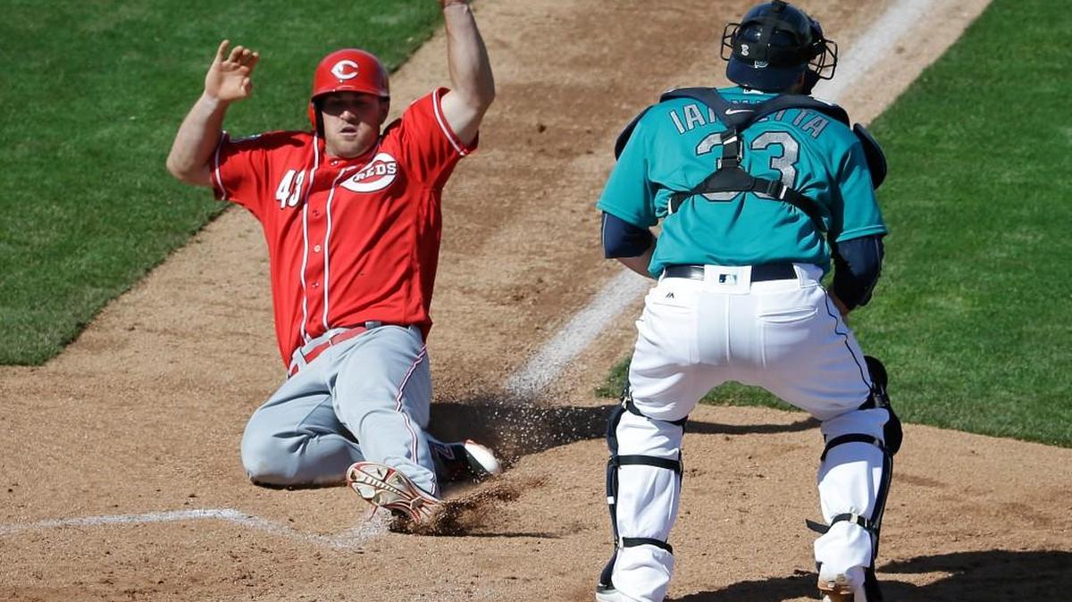 Scott Schebler slides safely into home for a Reds’ run in the sixth inning as catcher Chris Iannetta awaits a throw.